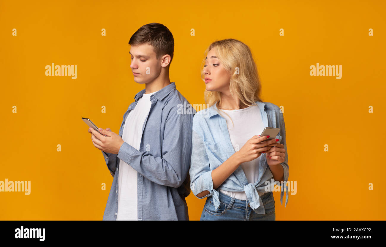 Jeune fille curieuse peeking comment son petit ami texting on phone Banque D'Images