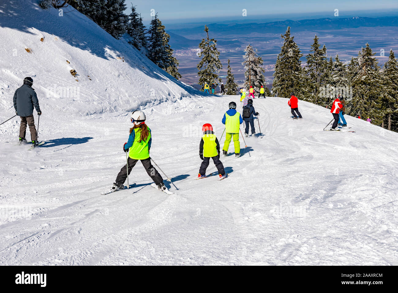 Groupe de personnes et enfants ski sur une pente de ski à Poiana Brasov resort, en saison d'hiver, Roumanie Banque D'Images
