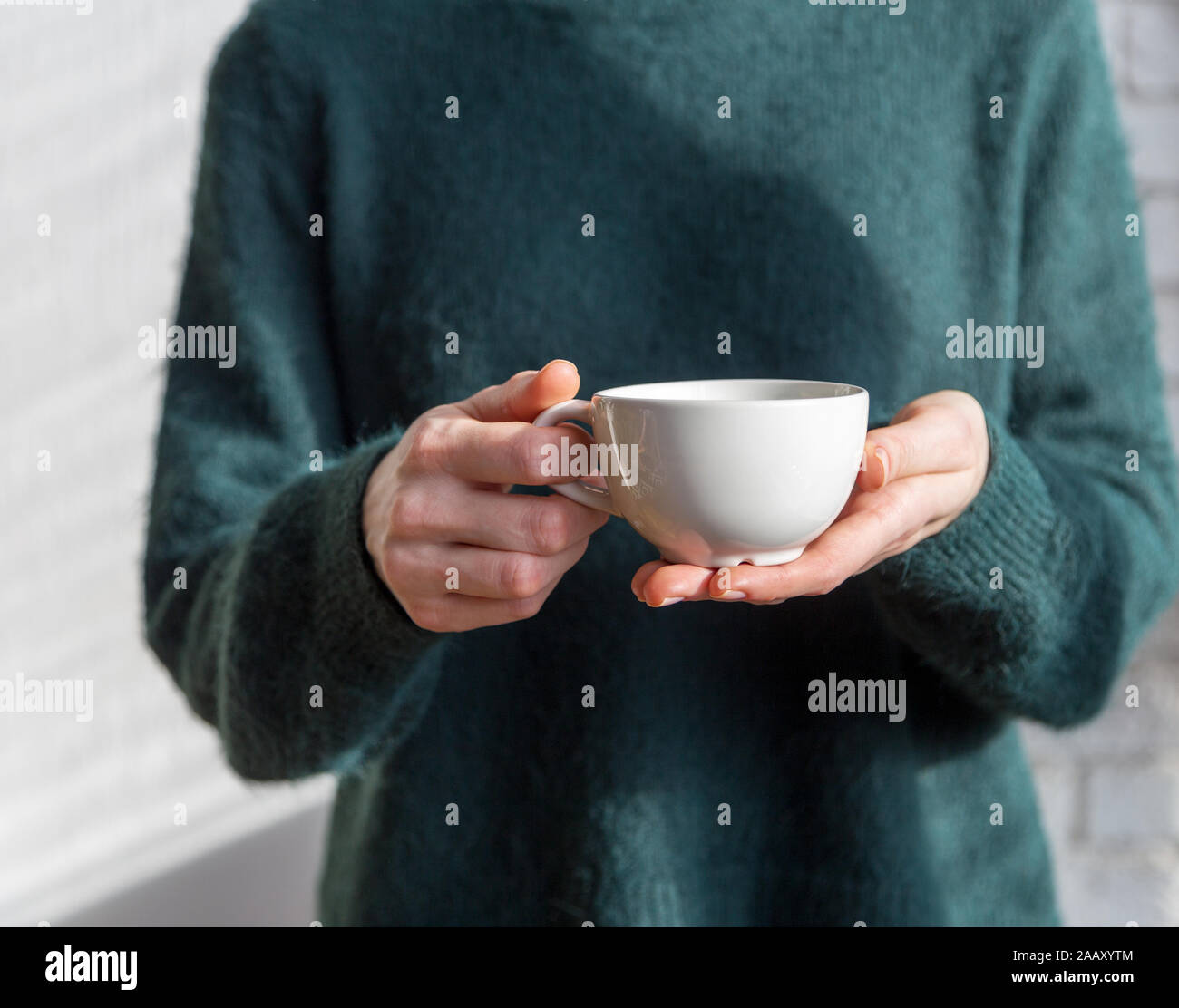 Thé ou café tasse in women's hands avec mur blanc à l'arrière-plan Banque D'Images