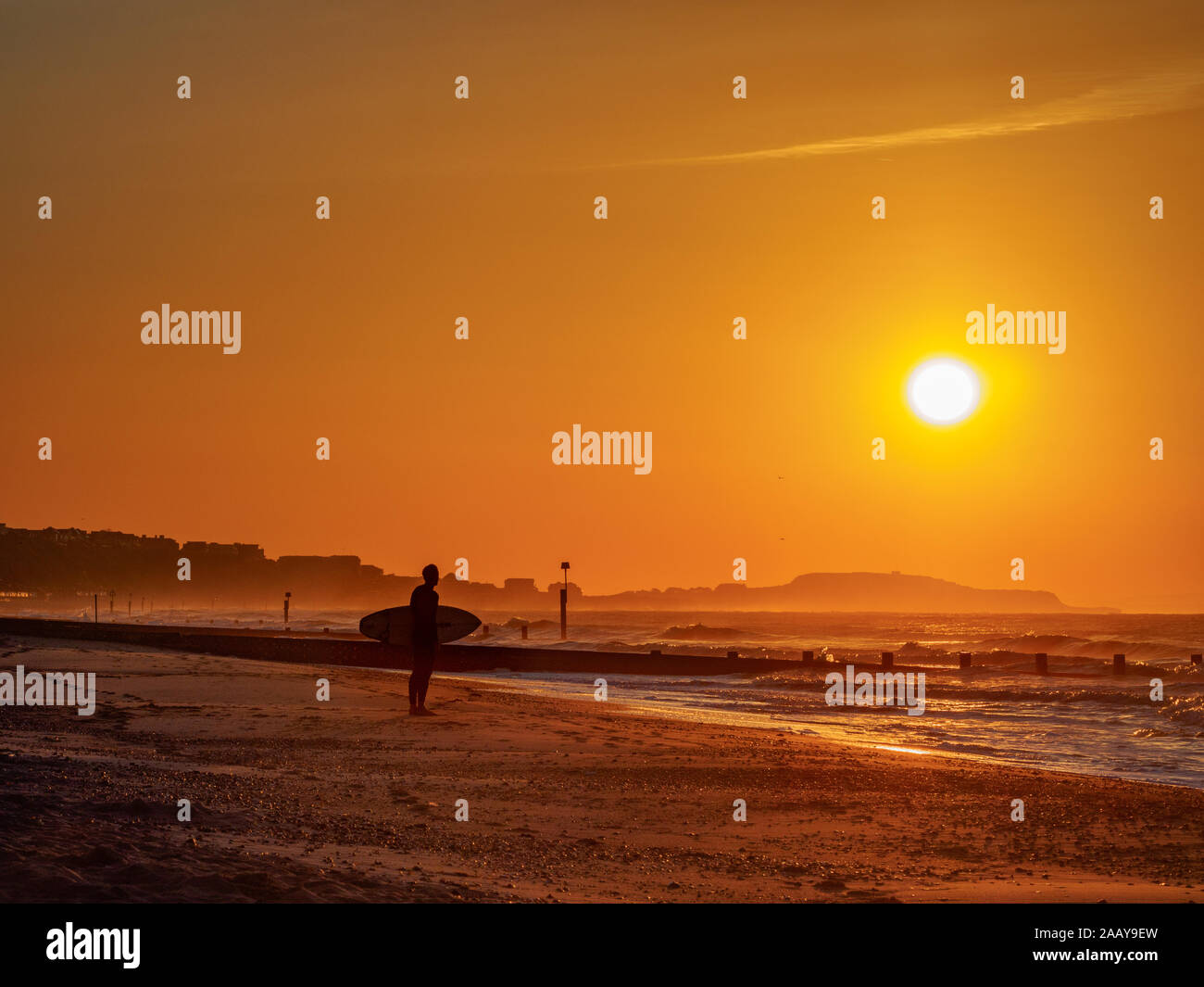 Un prepairs mornuning surfer pour le surf pendant une beautfil sunrise sur la plage de Bournemouth, Dorset, Angleterre. Banque D'Images