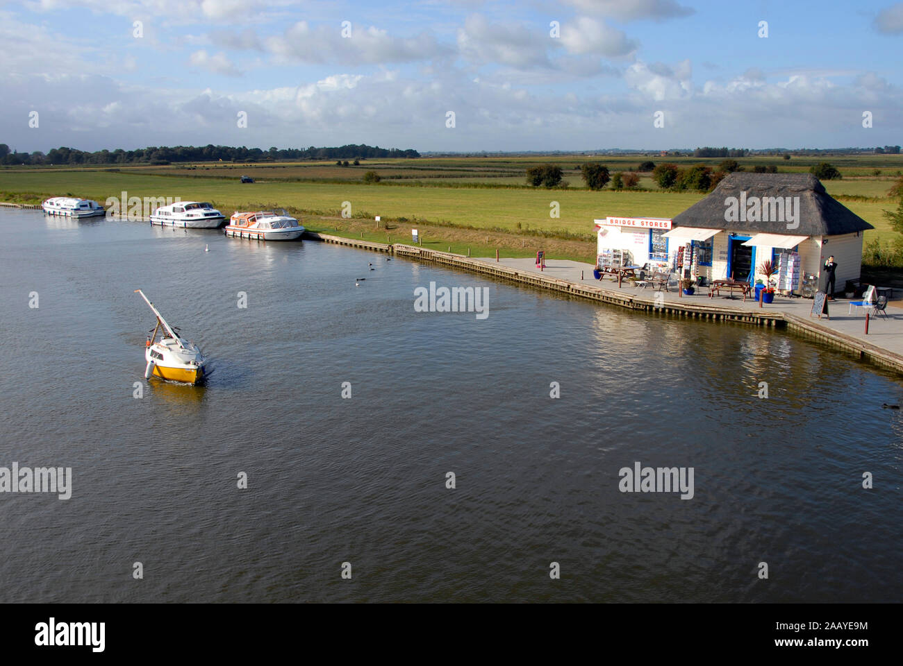 Marin solitaire sur rivière Bure, Norfolk Broads, en Angleterre avec le mât vers le bas et sous la puissance du moteur approche d'Acle bridge Banque D'Images