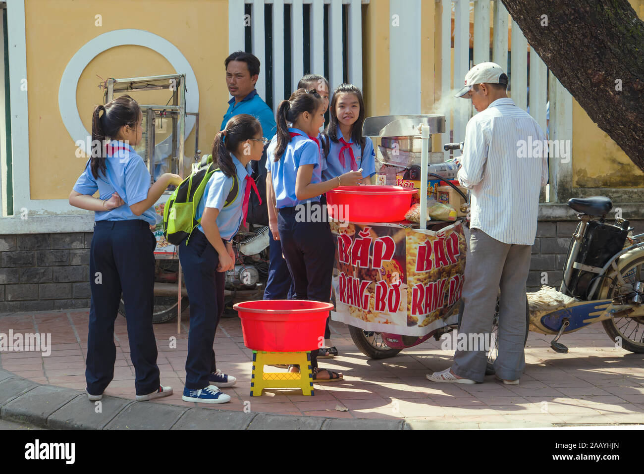 HUE, VIETNAM - janvier 08, 2016 : les écolières vietnamiennes acheter du maïs soufflé à un vendeur de rue Banque D'Images