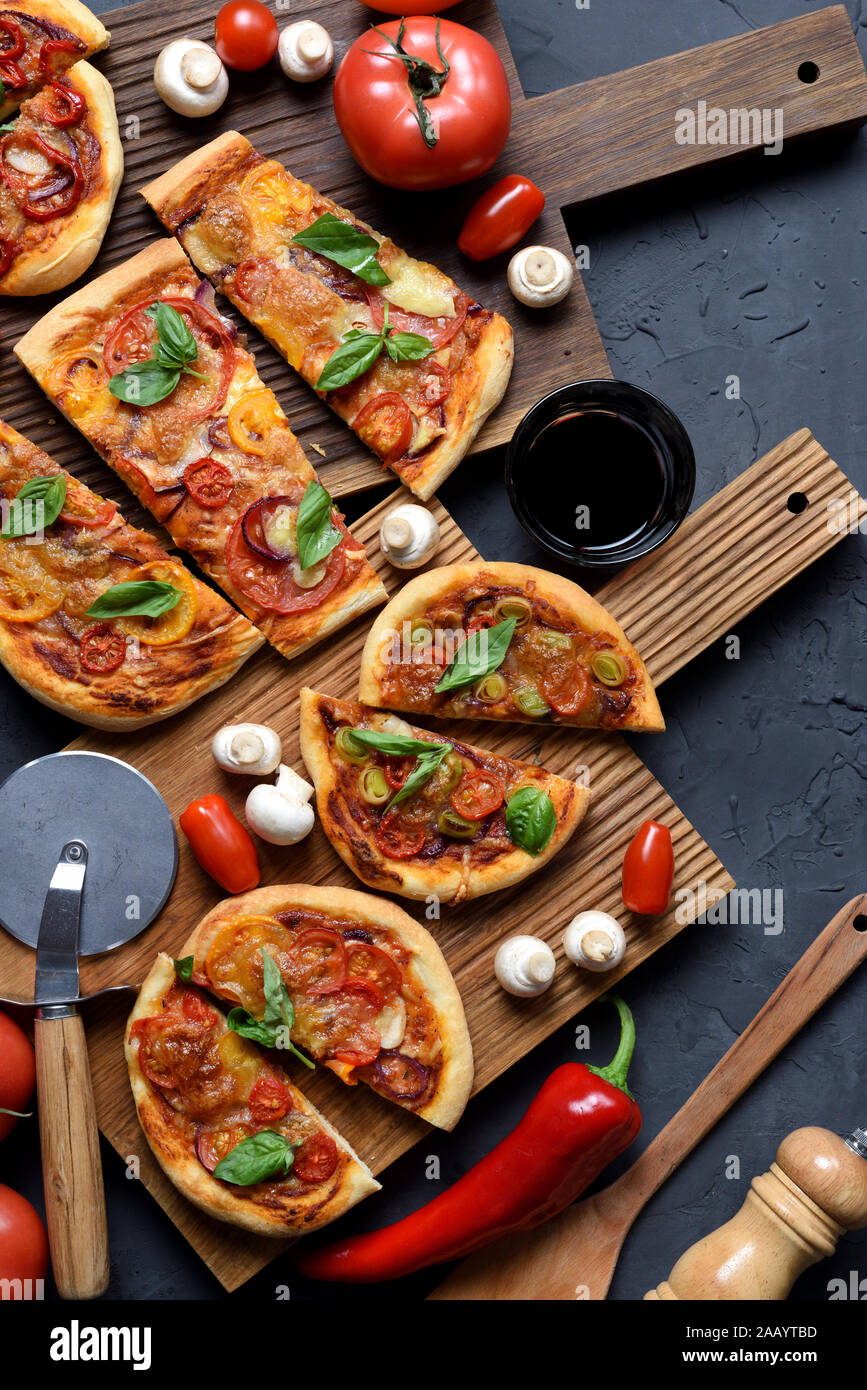 Flatlay abondante de pizza végétarienne partie. Pizzas maison rustique avec champignons, tomates et basilic servi avec du vin et des légumes crus sur oak board Banque D'Images