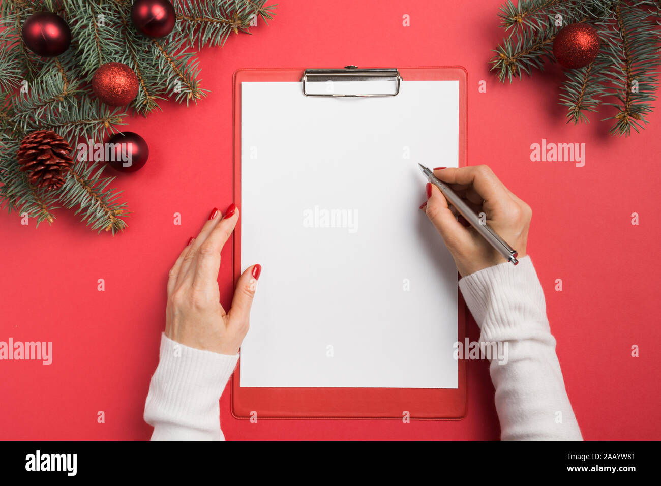Femme écrit objectifs, liste de vérification, plans et rêves pour la nouvelle année. Liste de souhaits pour Noël. Pour faire la liste pour l'année 2020 sur rouge. La planification des dépenses de cadeaux. Haut de la vie Banque D'Images