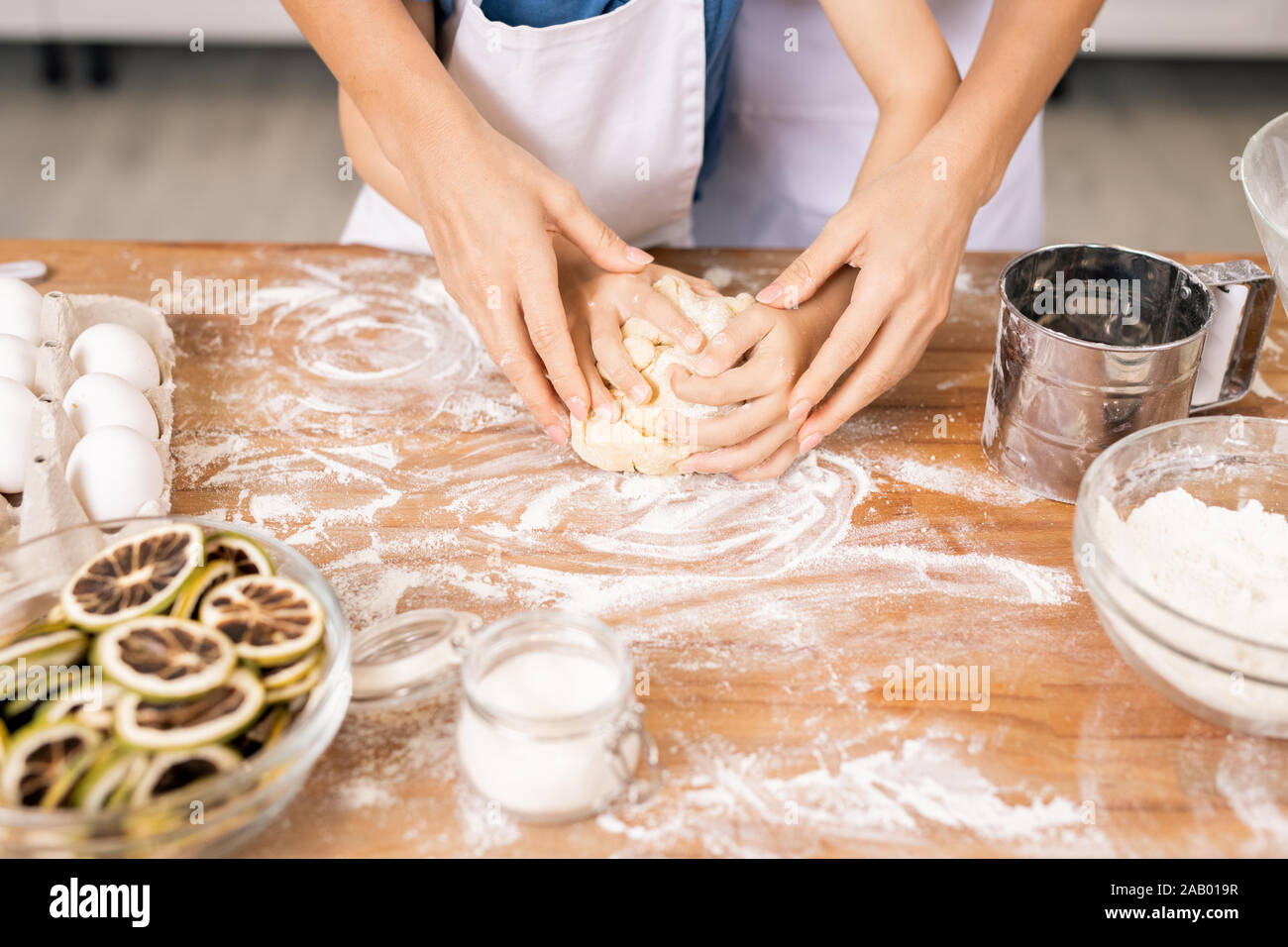 Les mains sur celles de petit garçon pour pétrir la pâte feuilletée sur une table de cuisine avant de faire des cookies Banque D'Images