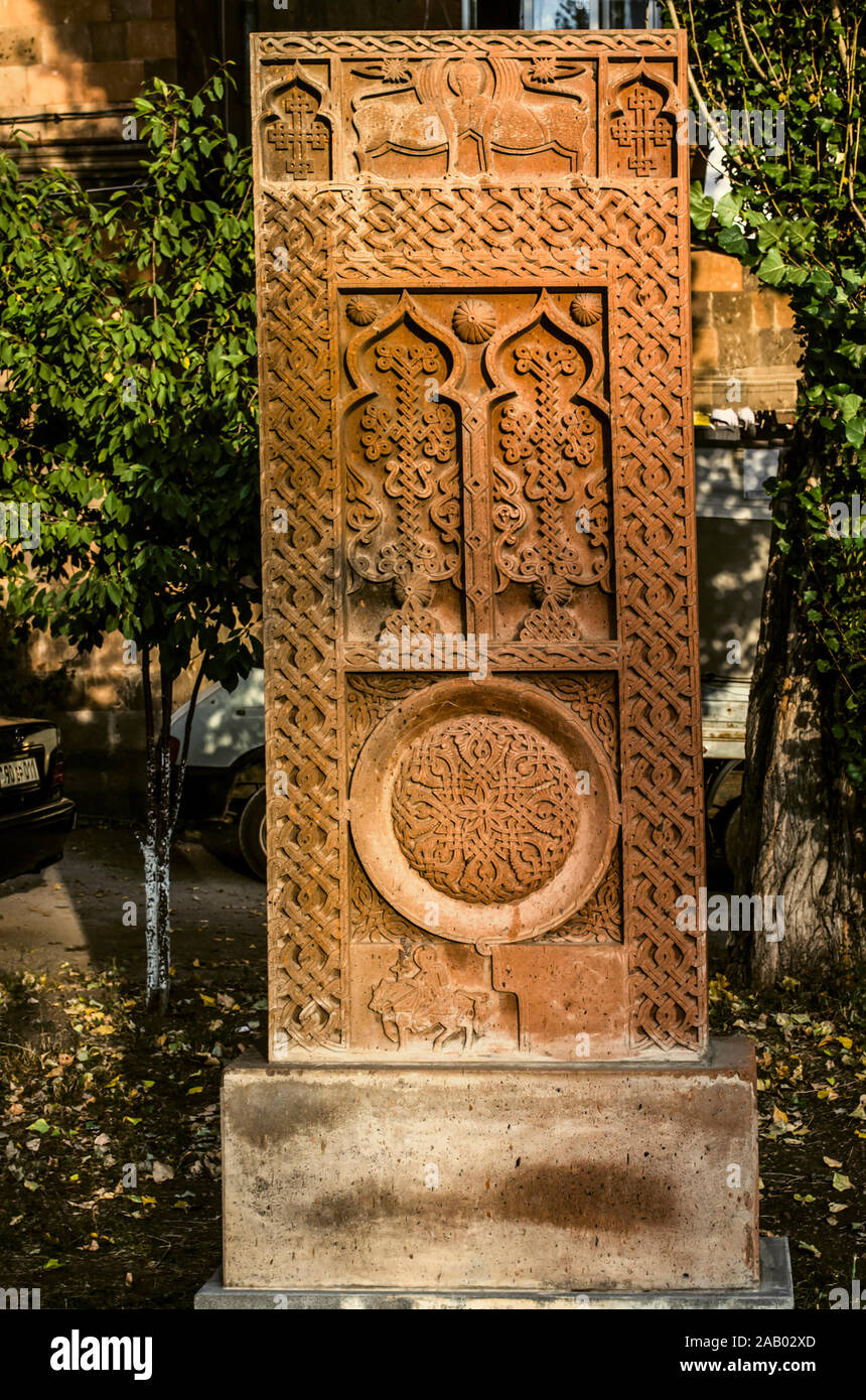 Khatchkar rouge avec animaux stylisés, deux arches avec des croisements, la figure d'un Saint sur un cheval, un symbole de l'éternité sur l'allée de croix en pierre en G Banque D'Images