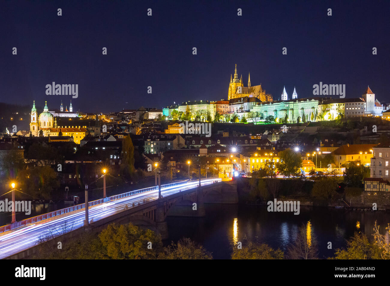 Château de Prague colorés au-dessus de la rivière Vltava dans la nuit. Cityscape with car light trails. Banque D'Images