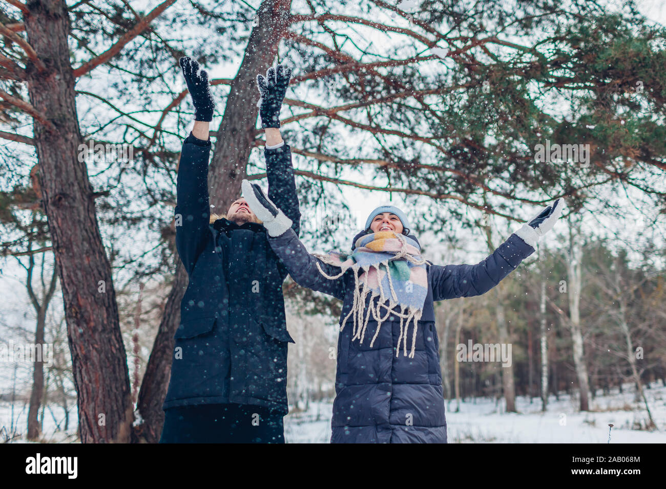 Activités d'hiver. Couple throwing snow en hiver forêt. Les gens se détendre et s'amuser en plein air Banque D'Images