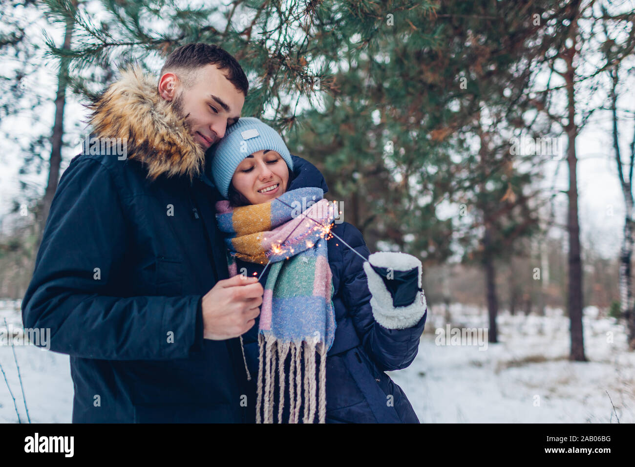 Couple aimant cierges brûlant dans la forêt d'hiver. Noël et Nouvel an concept. Les gens célébrant les jours fériés Banque D'Images