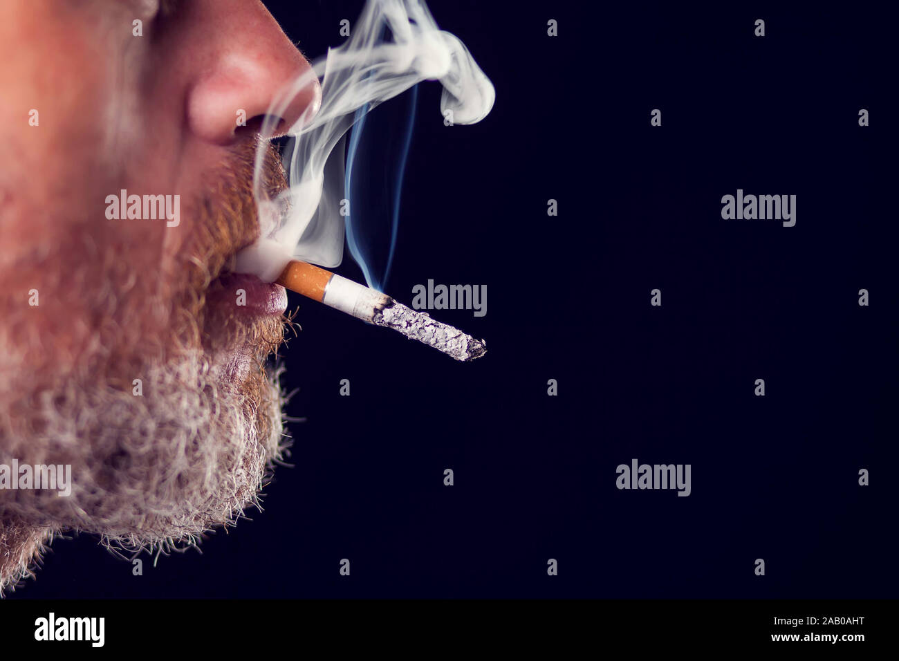 Un portrait de l'homme fume cigarette sur fond noir. Le concept de dépendance au tabac Banque D'Images