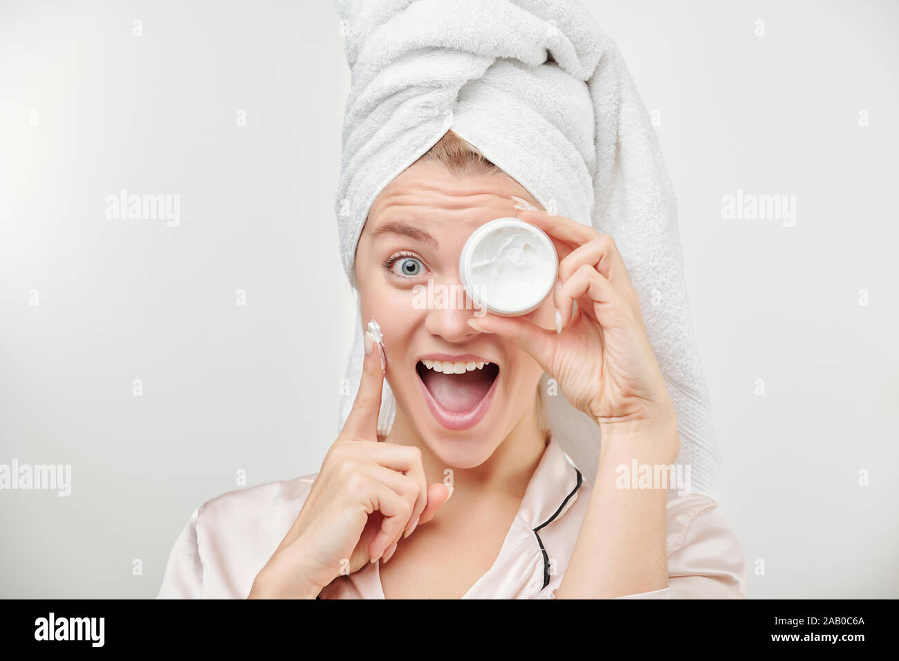 Fille excité avec towel on head holding pot de crème hydratante visage à l'oeil Banque D'Images