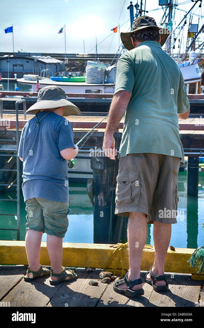 Vue arrière de l'homme et le garçon en tenue de la Californie, la pêche à partir d'un quai à la marina au Port de Santa Barbara Santa Barbara, CA Banque D'Images