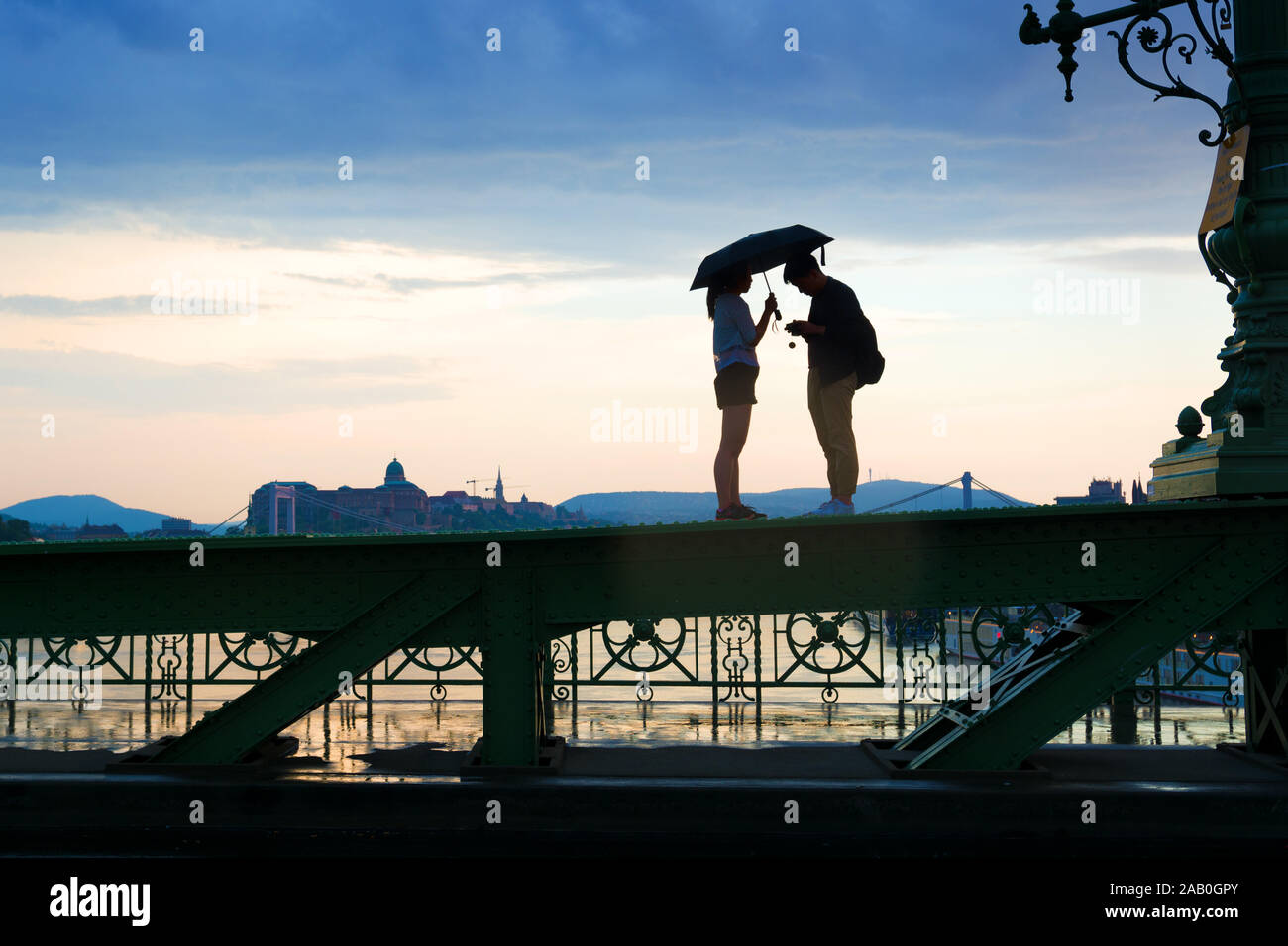 Silhouette de jeune couple debout sur un pont poutre avec caméra et ombrelle Banque D'Images
