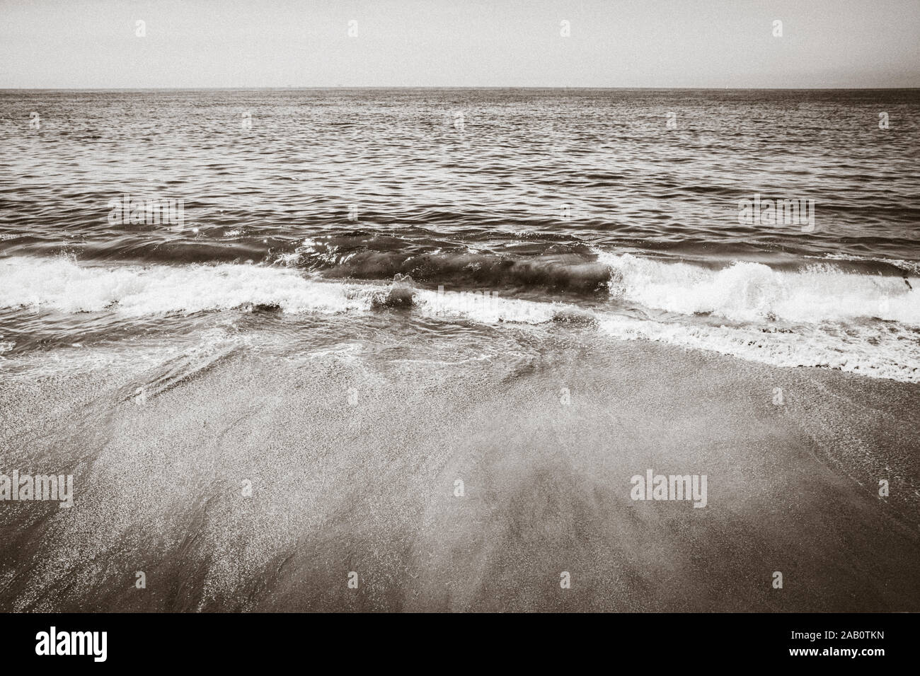 Vue grand angle de l'horizon qui se déroulent au-delà de petites vagues se brisant sur la plage de sable brun à Santa Barbara, CA, USA sépia Banque D'Images