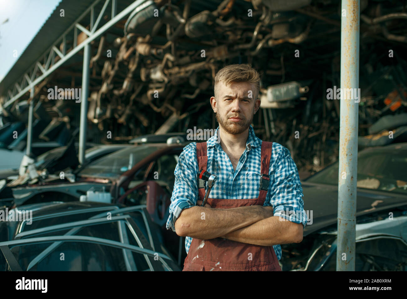 Homme mécanicien à la pile de voitures sur junkyard Banque D'Images