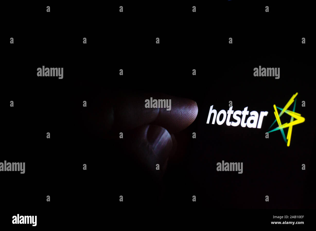 Hotstar streaming service logo à l'écran dans une pièce sombre et une main pointant sur elle. Hotstar est un service de diffusion de l'Inde. Banque D'Images