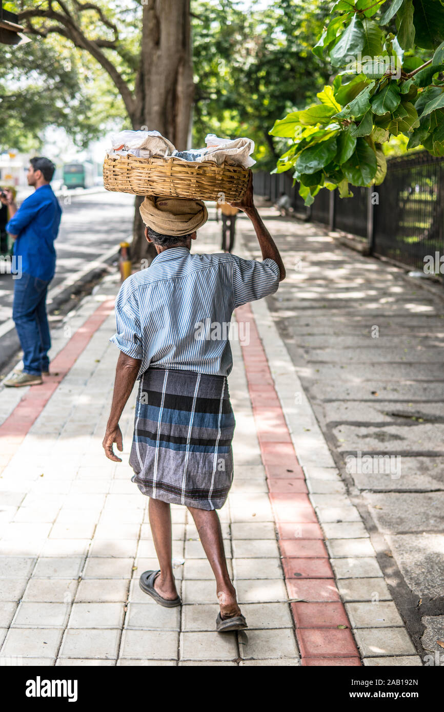 Bangalore, Inde, les rues de la ville de Bangalore, Inde hindoue old man carrying basket avec des cacahuètes pour la vente sur la tête, habillé dans lungi Banque D'Images