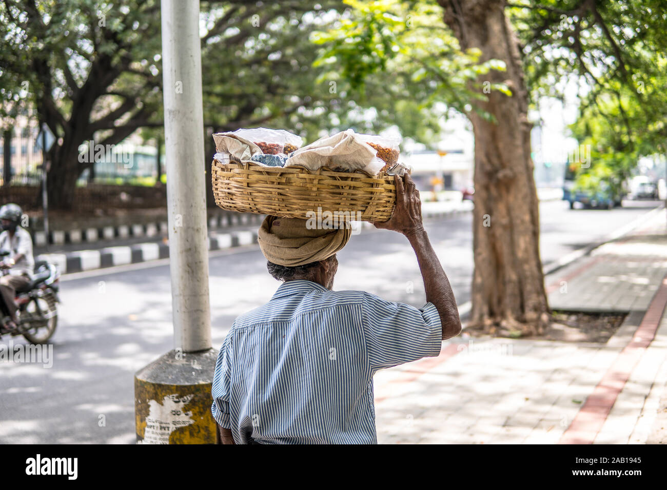 Bangalore, Inde, les rues de la ville de Bangalore, Inde hindoue old man carrying basket avec des cacahuètes pour la vente sur la tête, habillé dans lungi Banque D'Images