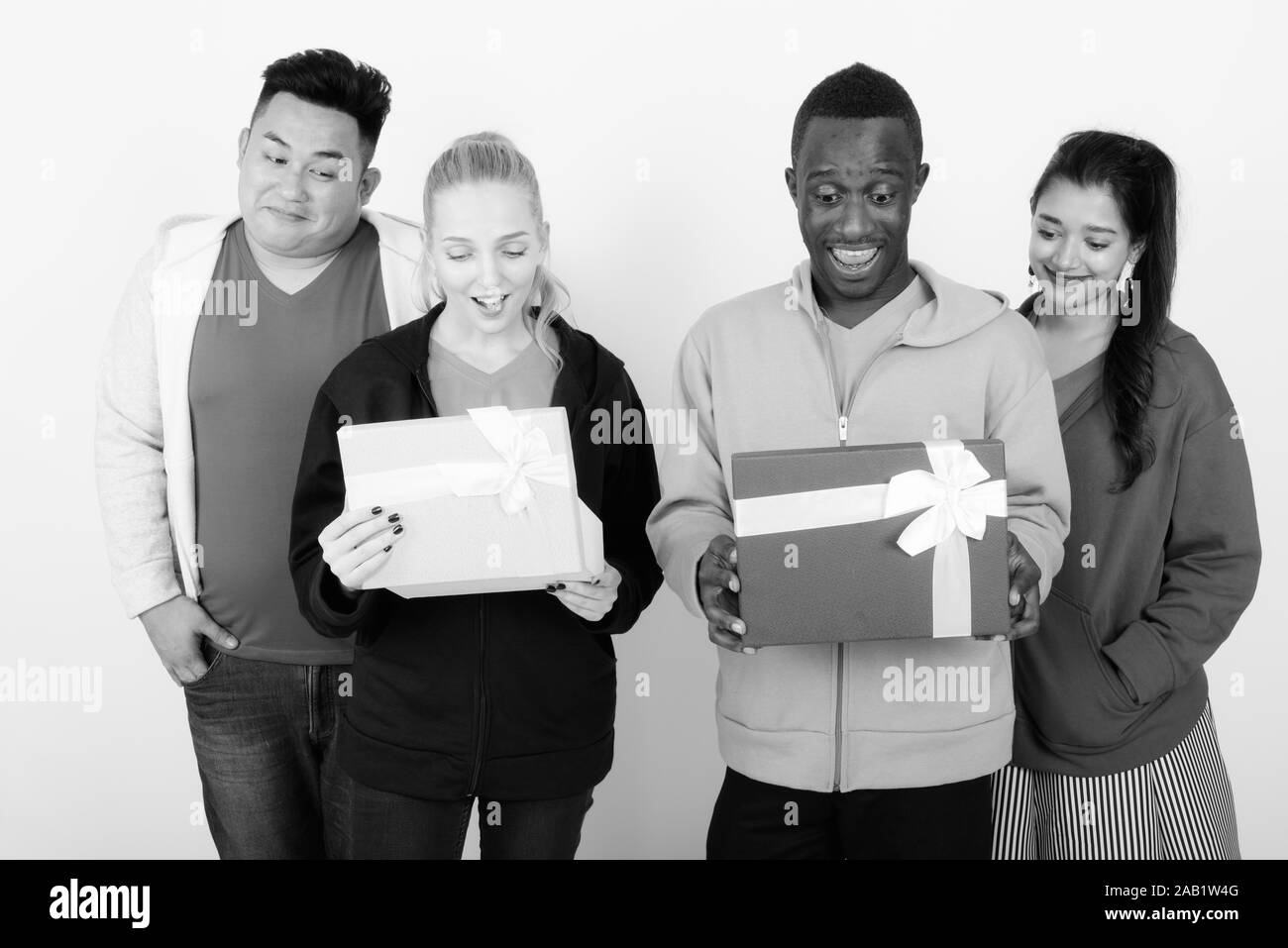 Studio shot of happy groupe diversifié de multi ethnic friends smiling lors de l'ouverture des boîtes-cadeaux et à surpris ensemble Banque D'Images