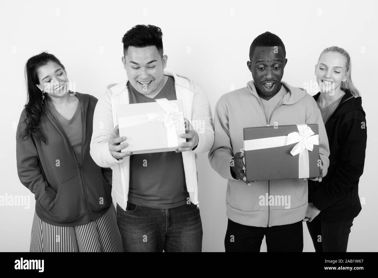 Studio shot of happy groupe diversifié de multi ethnic friends smiling lors de l'ouverture des boîtes-cadeaux et à choqué ensemble Banque D'Images