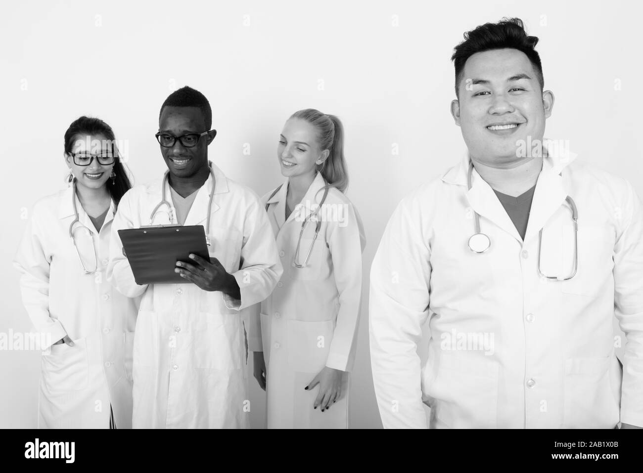 Portrait of happy Young Asian man médecin avec divers groupes ethniques de médecins de sourire et de penser lors de la lecture sur l'ensemble du presse-papiers Banque D'Images