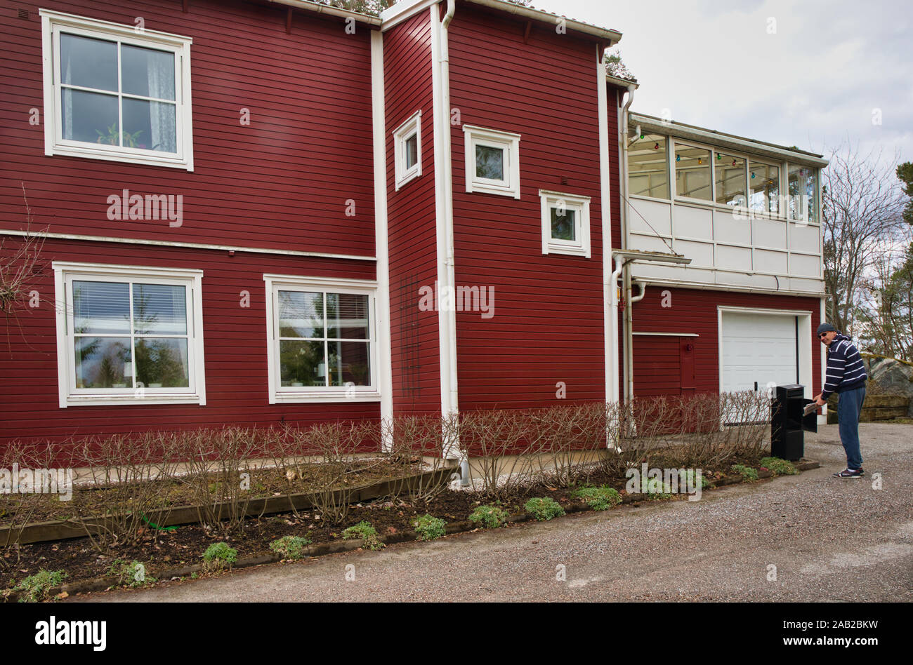 La collecte de l'homme de lettres à l'extérieur de la poste suédoise typique de la banlieue de Stockholm accueil, Upplands Vasby, Stockholm, Suède Banque D'Images