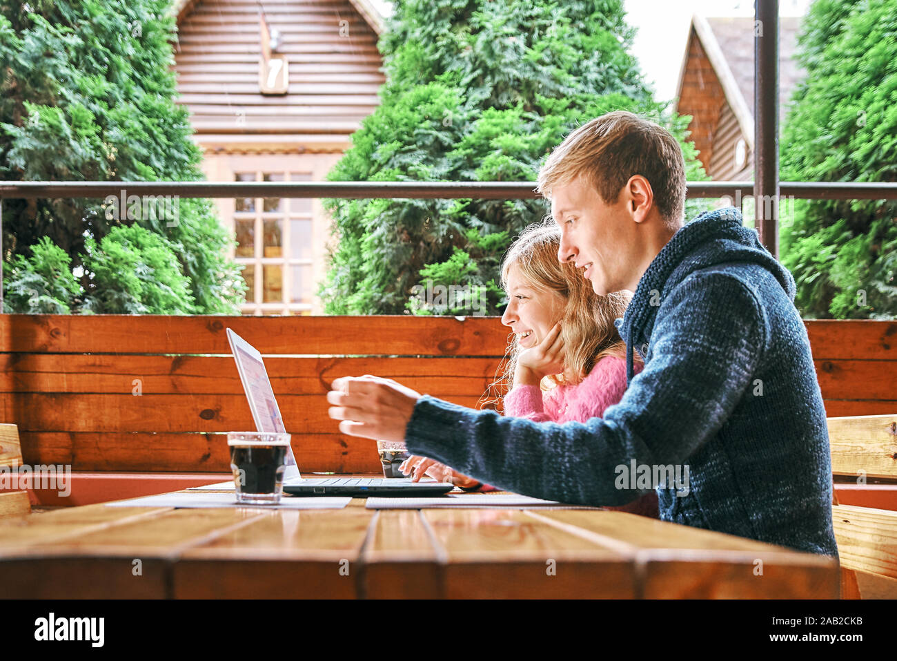 Jeune couple heureux dans un café à un ordinateur portable. L'homme et la jeune fille s'amusent ensemble et se détendre Banque D'Images
