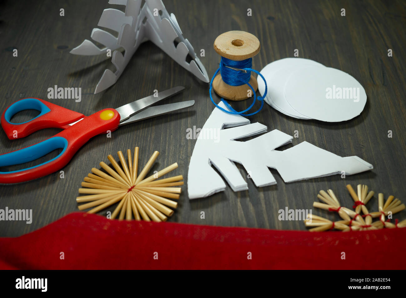 Fond Noël fête avec des décorations de Noël à partir de paille, de bonneterie chaîne et aux côtés du papier tissu rouge et une paire de ciseaux Banque D'Images