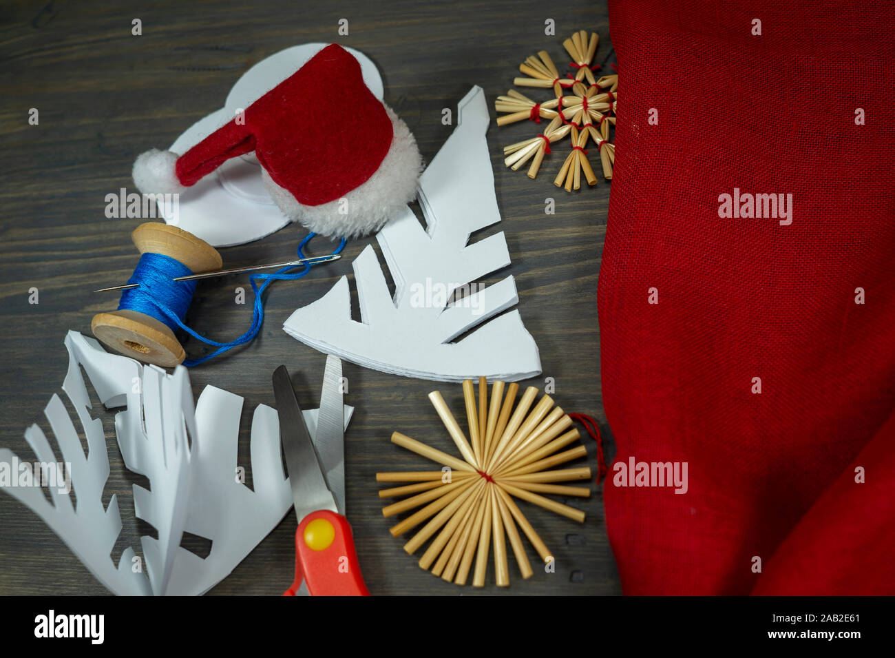 Fond Noël fête avec des décorations de Noël à partir de paille, de bonneterie chaîne et aux côtés du papier tissu rouge et une paire de ciseaux Banque D'Images