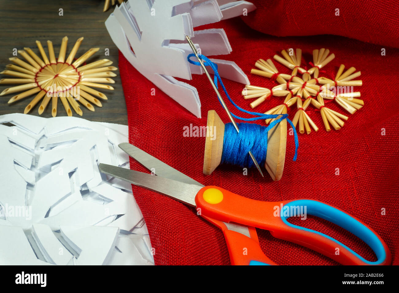 Fond Noël fête avec des décorations de Noël à partir de paille, de bonneterie chaîne et aux côtés du papier tissu rouge et une paire de ciseaux Banque D'Images