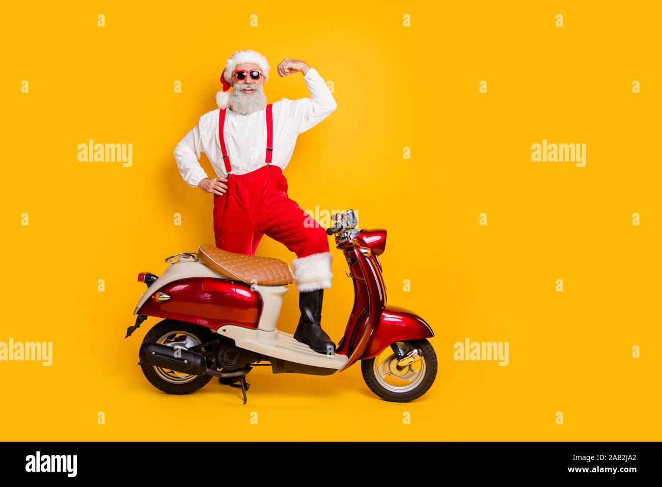 Corps complet de santa photo homme ambitieux se tiennent près de cyclomoteur montrent la force des biceps livré des cadeaux à la mode d'usure pantalons shirt sun specs pac isolés Banque D'Images