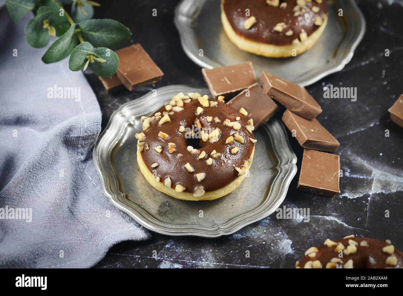 Boulangerie savoureux donut chocolat avec vitrage et l'écrou nutrifer organisé sur fer à repasser plateau avec morceaux de chocolat en en arrière-plan Banque D'Images
