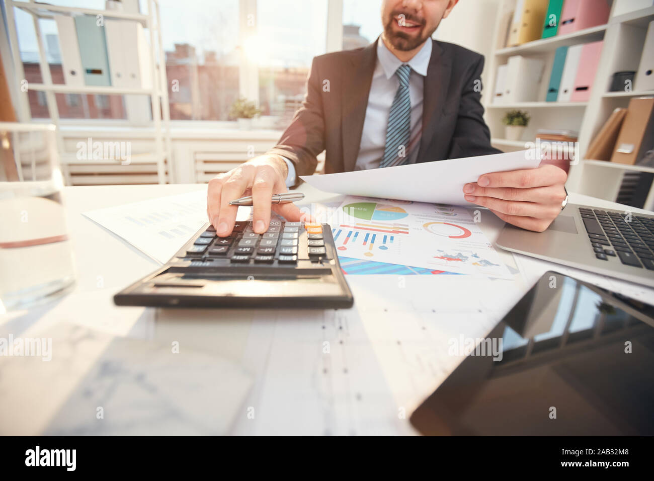 De gros plan homme méconnaissable le calcul des dépenses d'entreprise tandis que sitting at desk in office, focus on hand en appuyant sur les touches de la calculatrice, copy space Banque D'Images