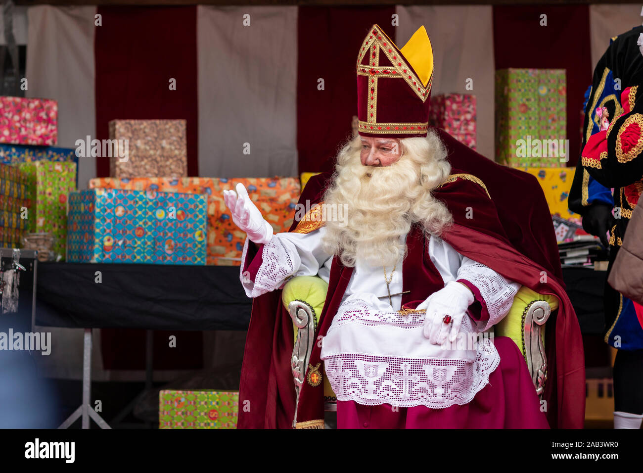 Eindhoven (Pays-Bas), 23 novembre 2019. Sinterklaas portant son costume assis sur une chaise en agitant pour enfants. Enveloppé dans les cadeaux colorés Banque D'Images