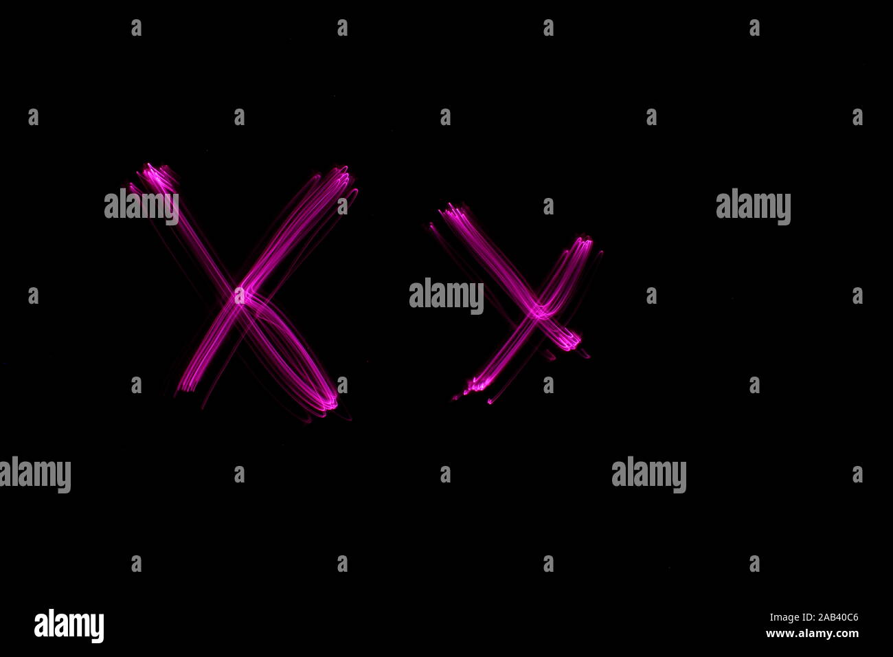 Une longue exposition photographie de la lettre x de couleur rose, en majuscules et minuscules, motif de lignes parallèles sur un fond noir. Banque D'Images