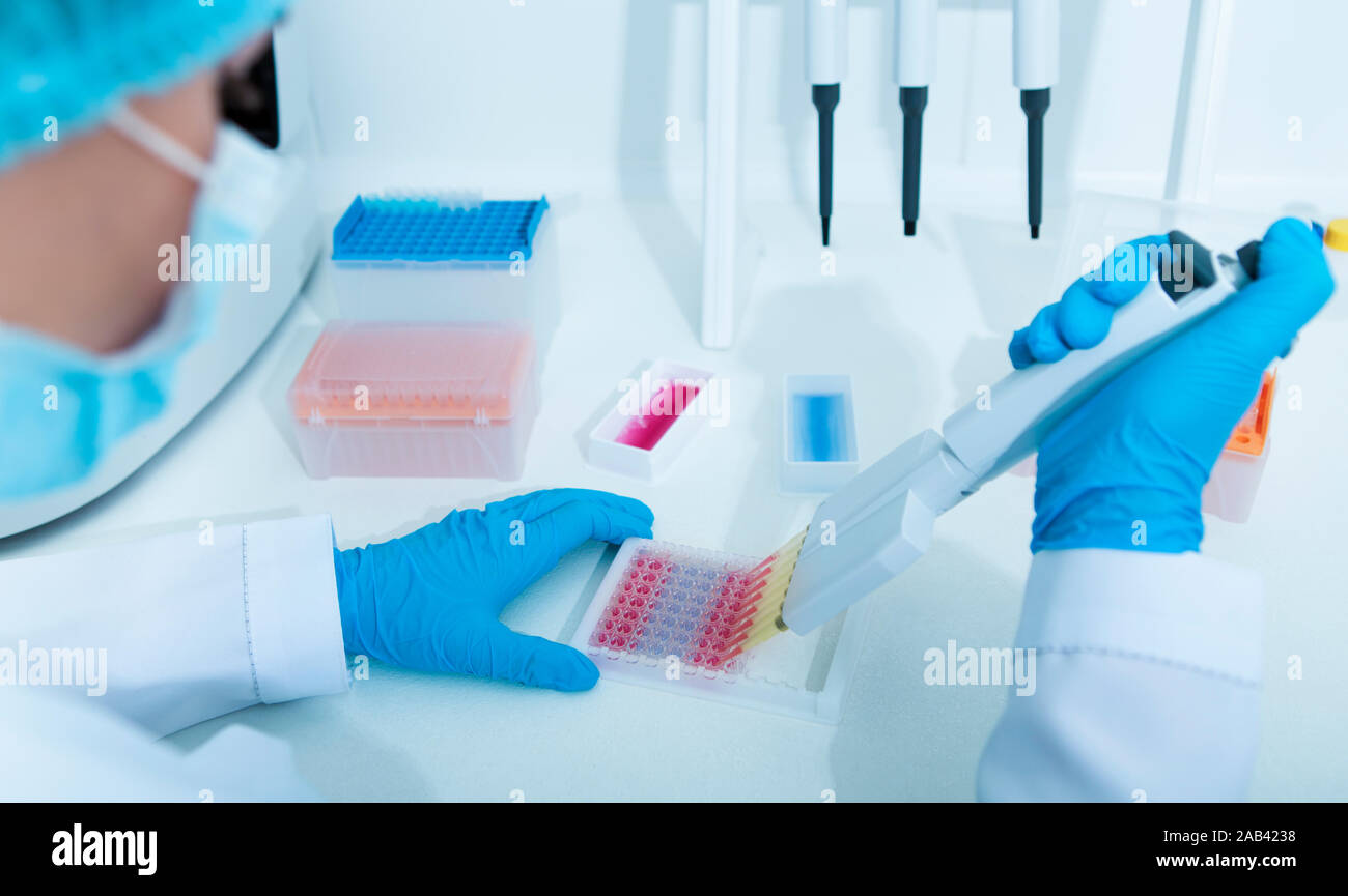 Femme scientifique rempli dans des tubes à essai avec des échantillons de couleur Banque D'Images