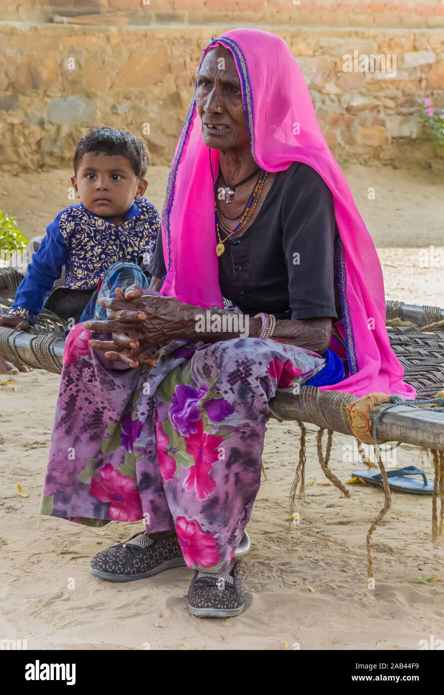 Vieille Femme et enfant assis sur un banc dans les zones rurales du Rajasthan, Inde Banque D'Images