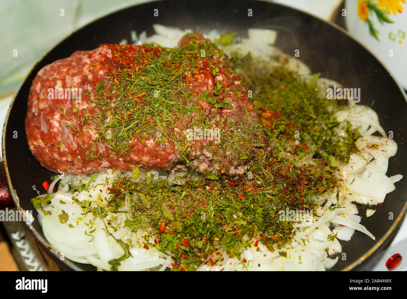 Hacher la viande hachée à l'oignon et les légumes secs à l'aneth avec des épices dans une poêle de la cuisine maison. Processus de cuisson. Banque D'Images