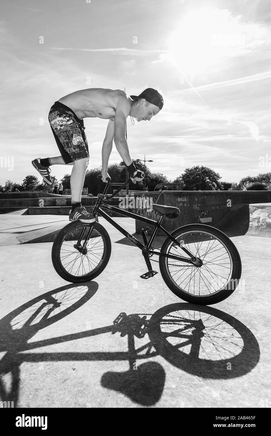 Un jeune à l'échelle locale skatepark pratiquer sur son BMX, équitation autour du skatepark faisant des tours et de sauter haut comme suit Banque D'Images