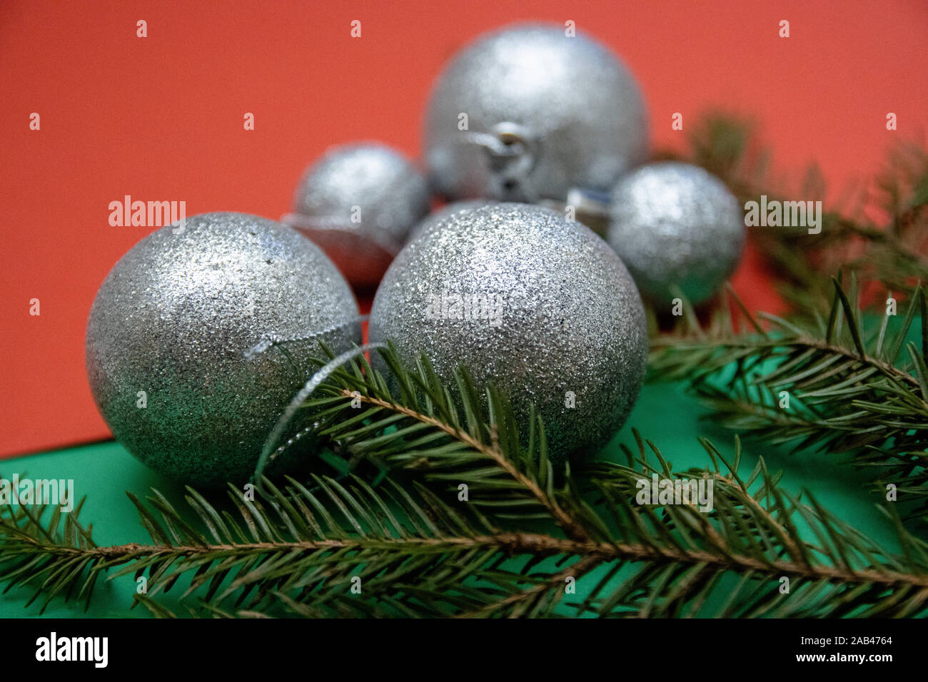 Photos de Noël avec des boules d'argent et de branches de conifères sur un fond vert-rouge Banque D'Images