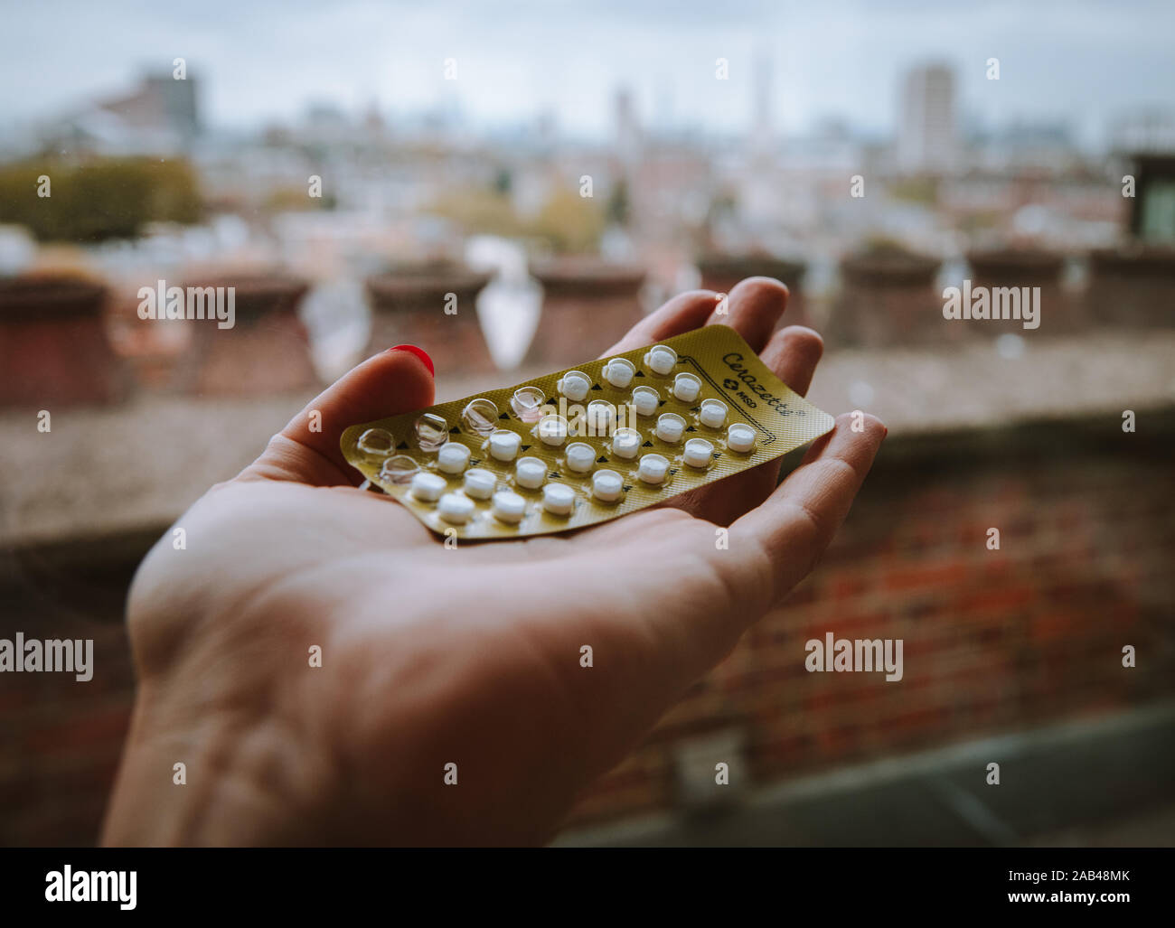 Pilule contraceptive tenant dans une main à l'extérieur Banque D'Images