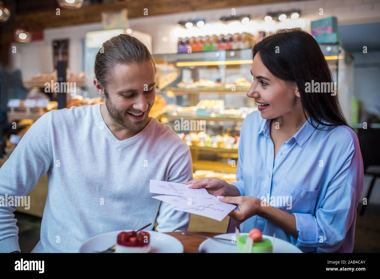 Femme en souriant tout en montrant son futur mari les invitations de mariage Banque D'Images