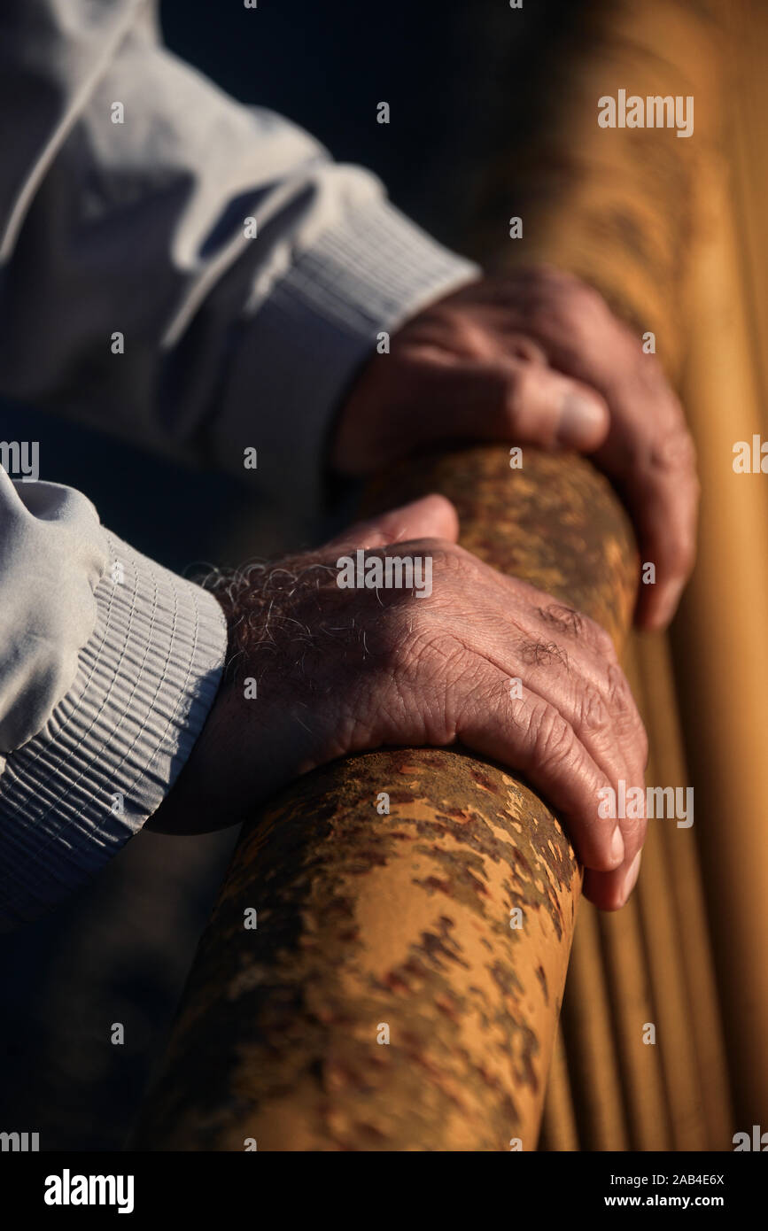Middle-aged man's hands sur une balustrade d'un vieux pont métallique Banque D'Images
