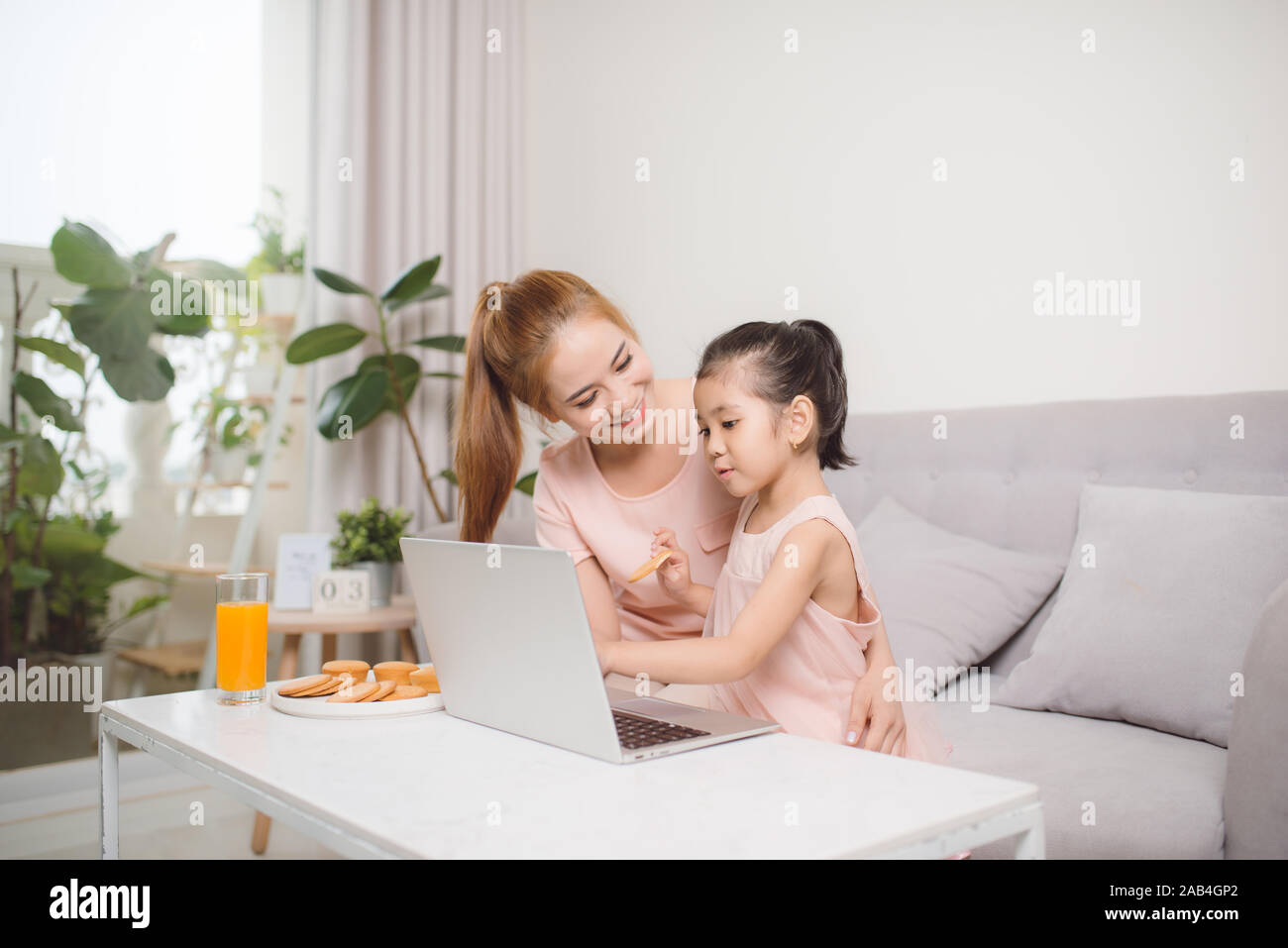 Mère et fille de l'emplacement sur le canapé et using laptop Banque D'Images
