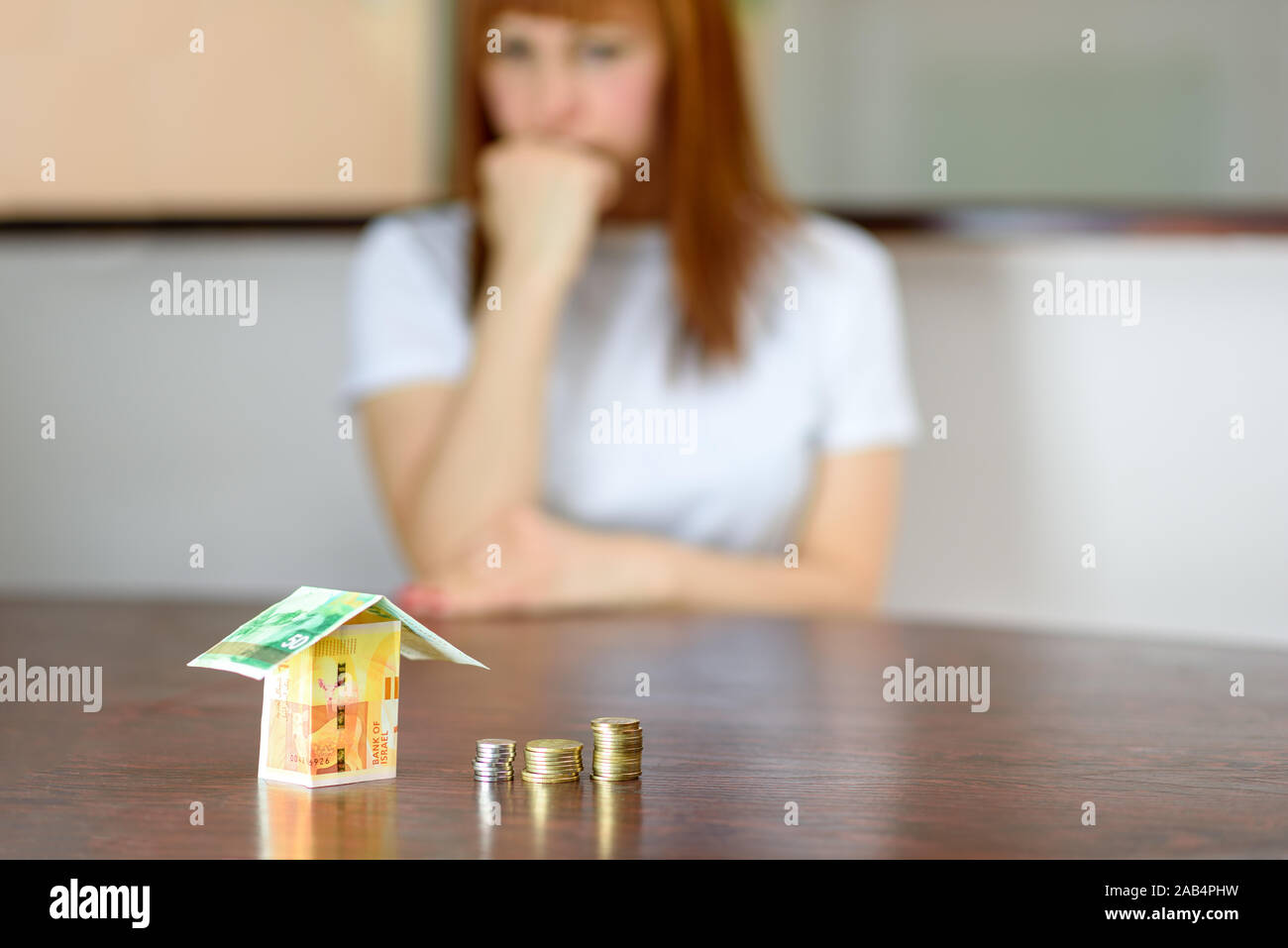 Femme d'âge moyen modèle avec chambre d'Israël Devises nouveau shekel israélien sur la table en bois. Woman relaxing at home, bâtiment maison d'Israël et 50 100 billets en euros.Selective focus sur l'argent. Banque D'Images