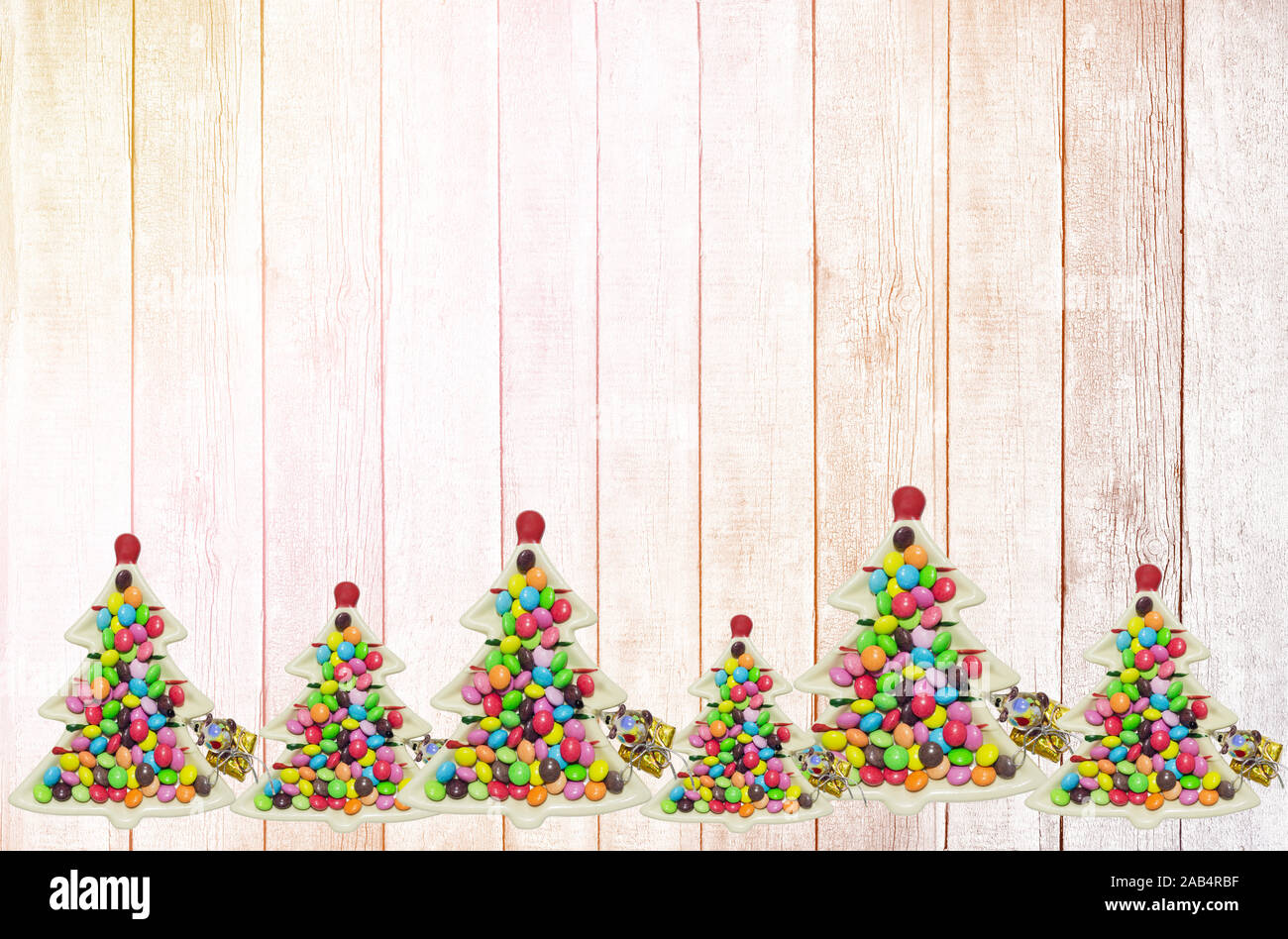 Des assiettes en forme d'arbres de Noël avec des bretzels et des bonbons décorent le fond en bois. Jouet en verre amusant et décorations d'arbre de Noël Banque D'Images