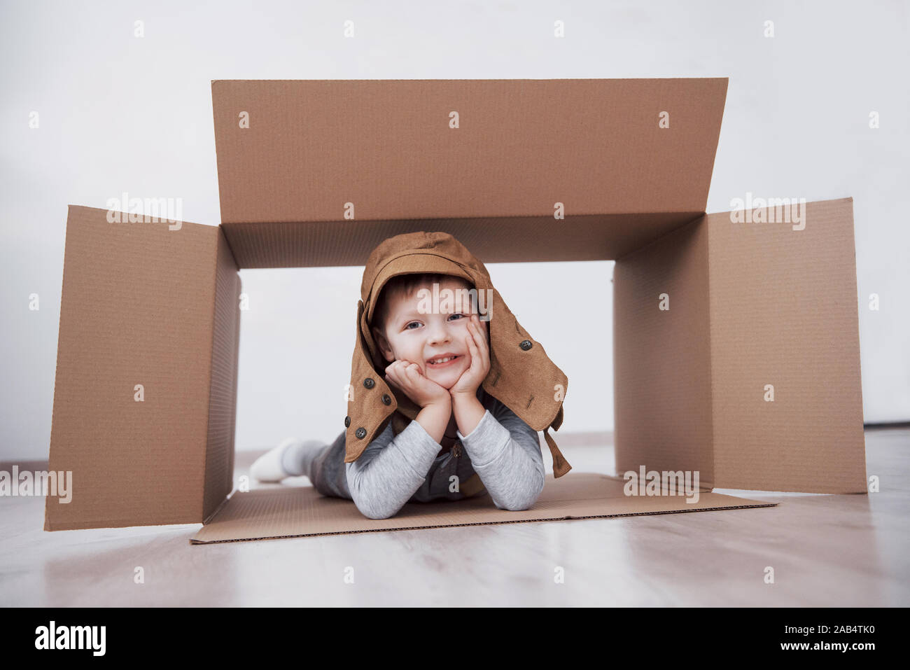 La petite enfance ludique. Petit garçon s'amuser grâce à la boîte de carton. Garçon prétendant être pilote. Little Boy and girl having fun at home Banque D'Images