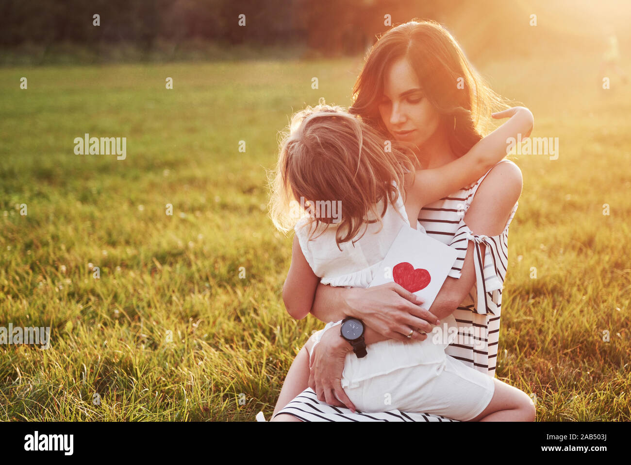 La fille de l'enfant félicite sa mère et lui donne une carte postale. Mère et fille sourire et Hug. Banque D'Images