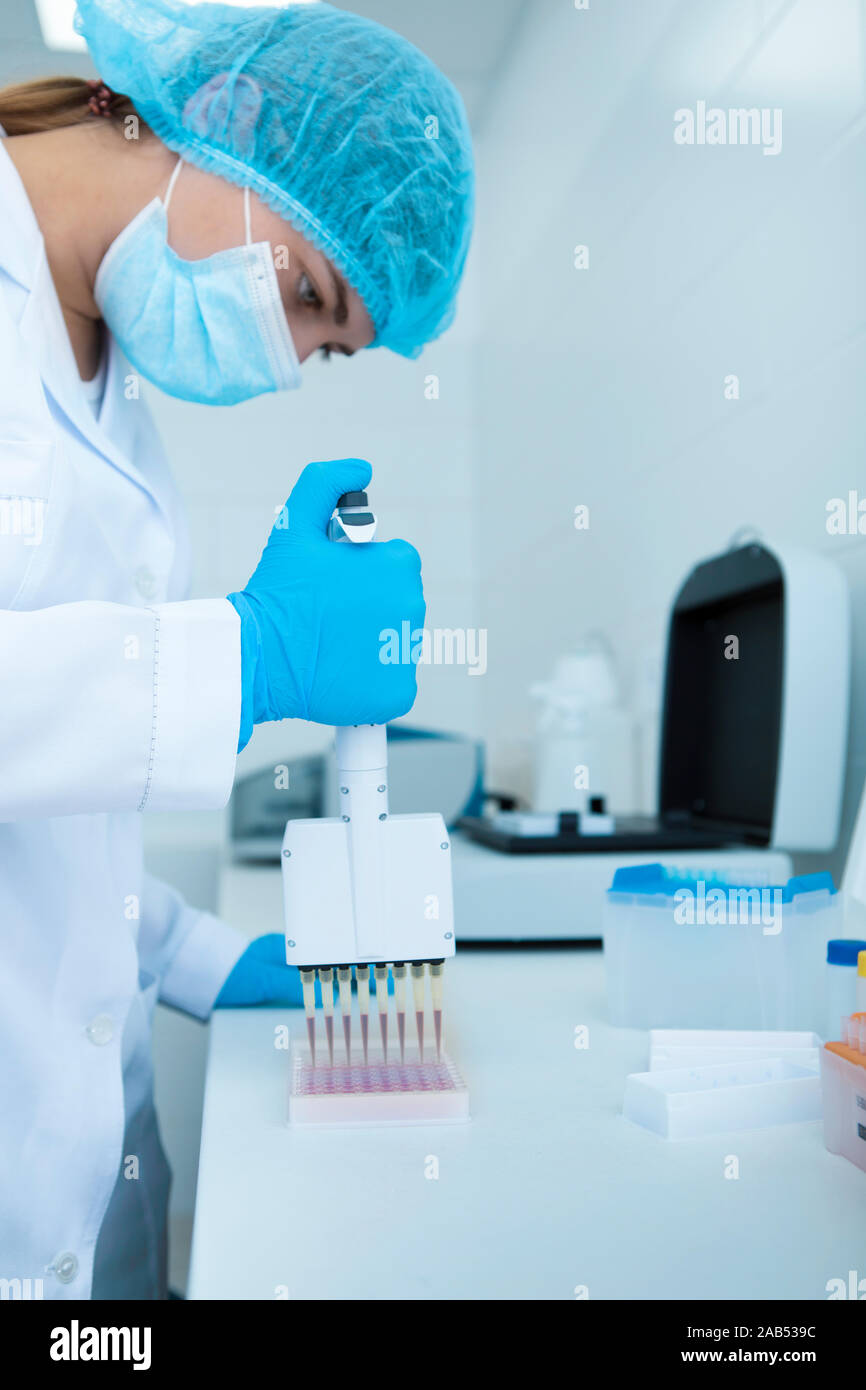 Young female scientist gouttes échantillons rouge dans des tubes à essai Banque D'Images