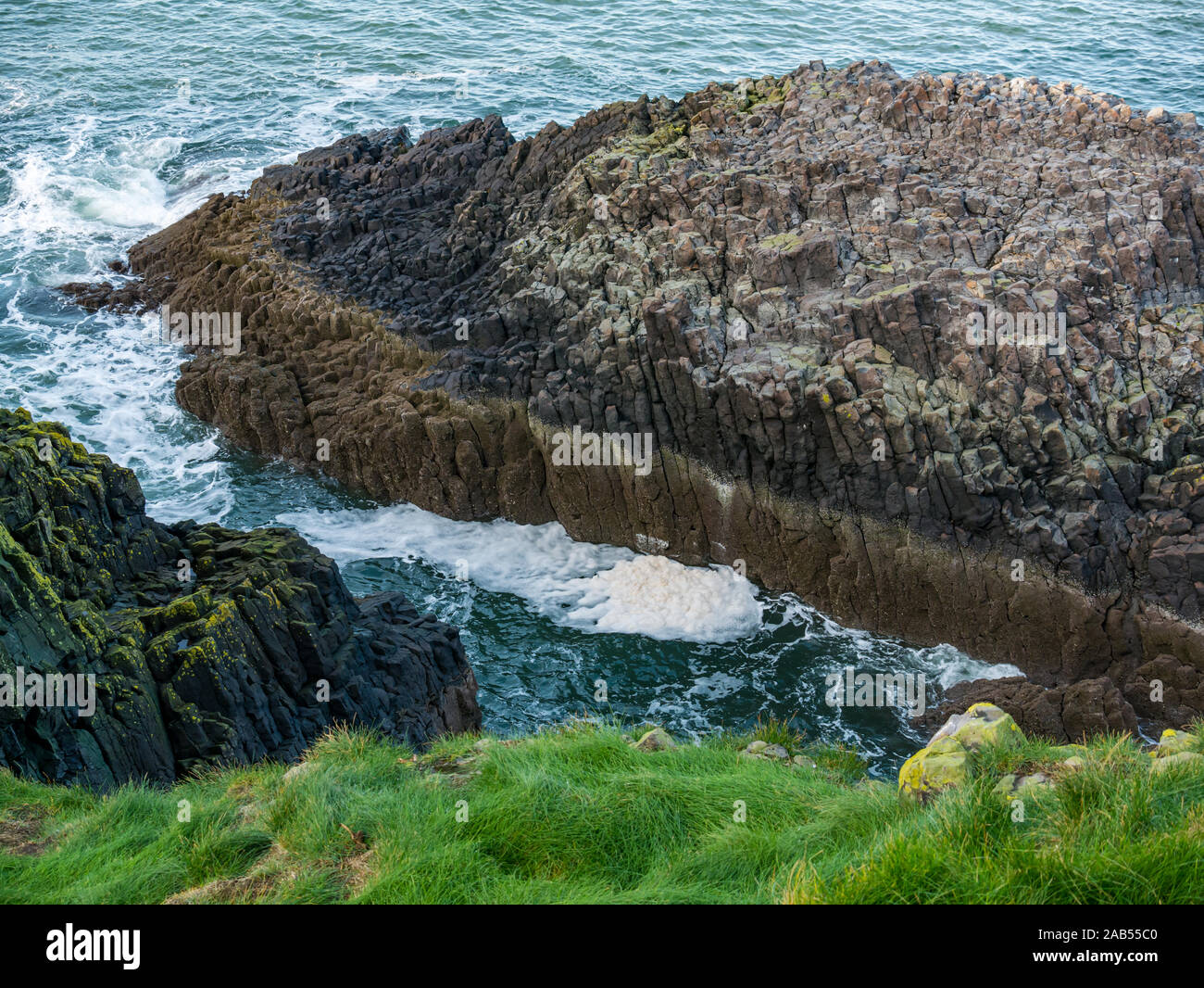 Mousse, mousse et des vagues sur un rivage rocailleux de basalte de l'île d'entrée, de l'agneau, Firth of Forth, Ecosse, Royaume-Uni Banque D'Images